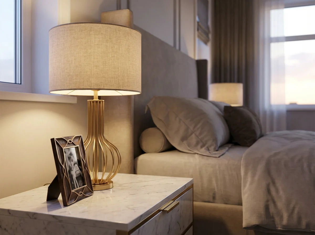 Gold base bedside table lamp with beige linen drum shade warm glow luxury bedroom