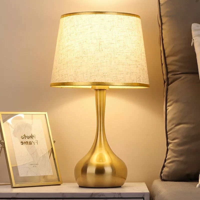 Danish postmodern gold base table lamp with linen shade on marble nightstand bedroom
